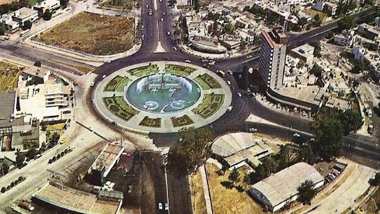 Portada del documental: vista aérea de archivo de una glorieta con fuente rodeada de avenidas y edificios.